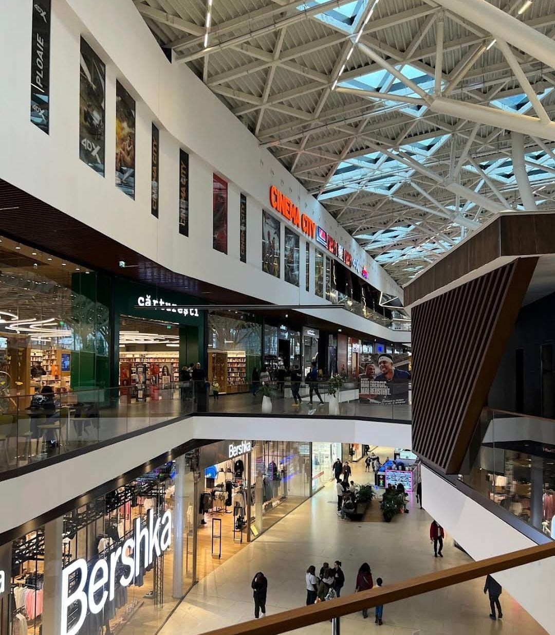 Due livelli di gallerie all'AFI Brașov sotto il tetto di vetro, con Bershka in basso, Cărturești sopra e l'insegna del Cinema City all'ultimo piano