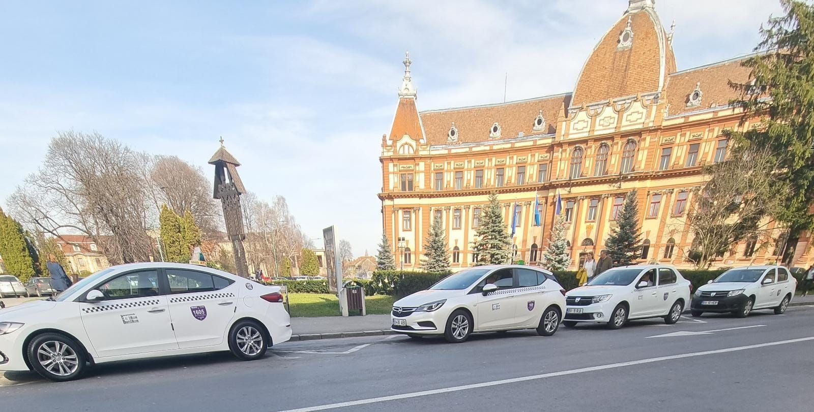Row of white licensed taxis waiting at a rank in central Brașov