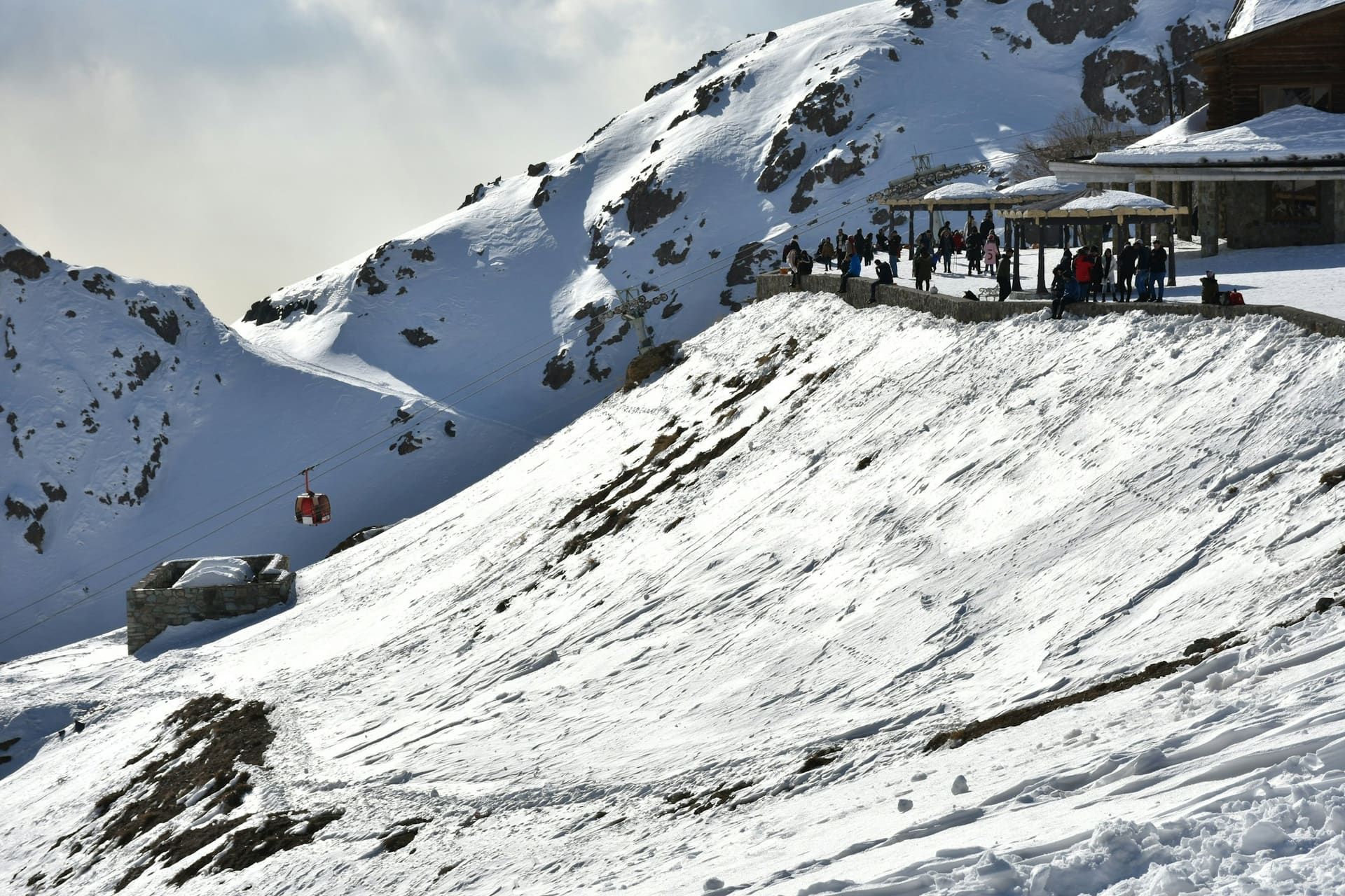 Red cable cars passing above a snowy valley