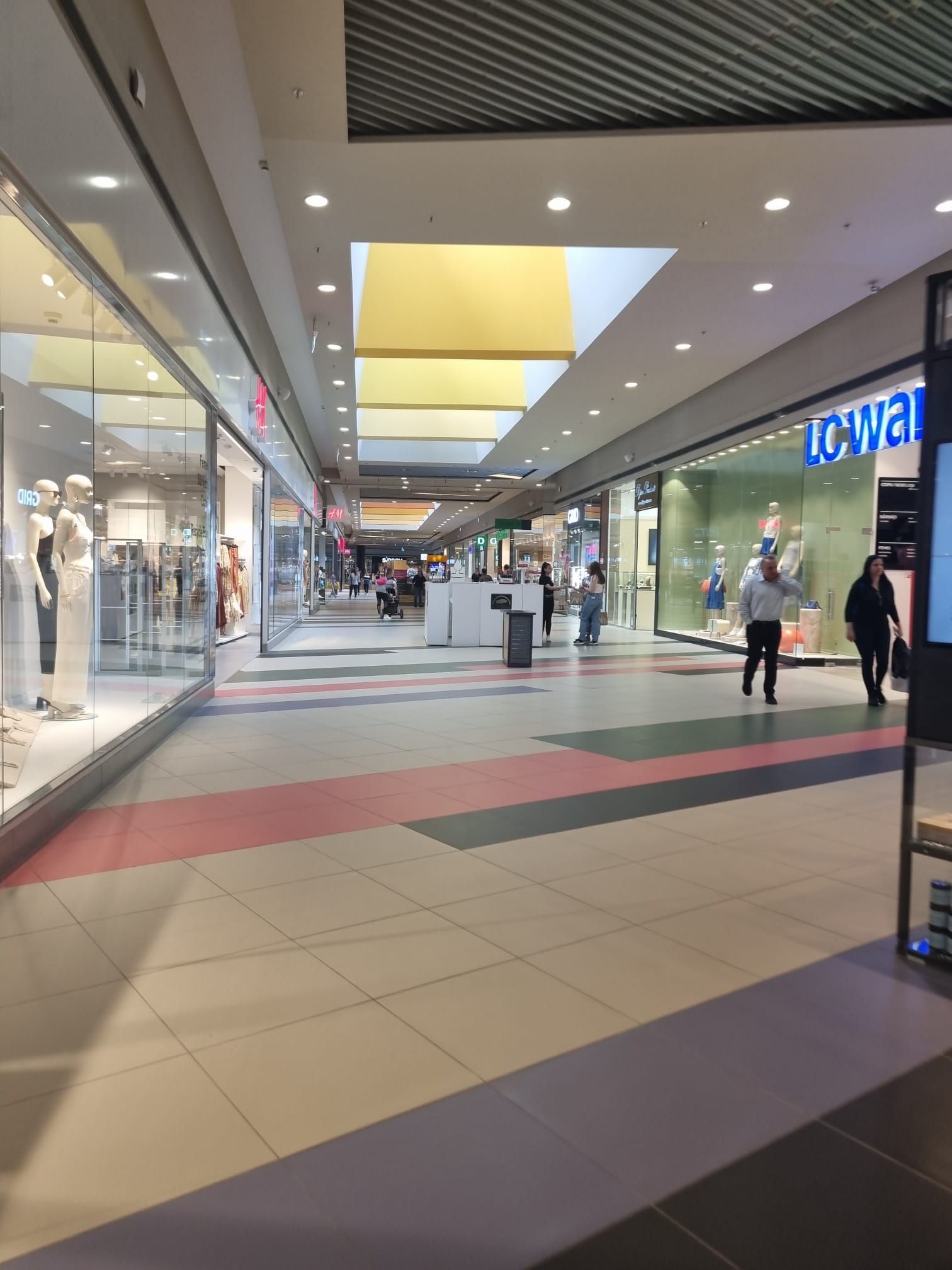 A long, bright shopping gallery inside Coresi with H&M on the left and LC Waikiki on the right