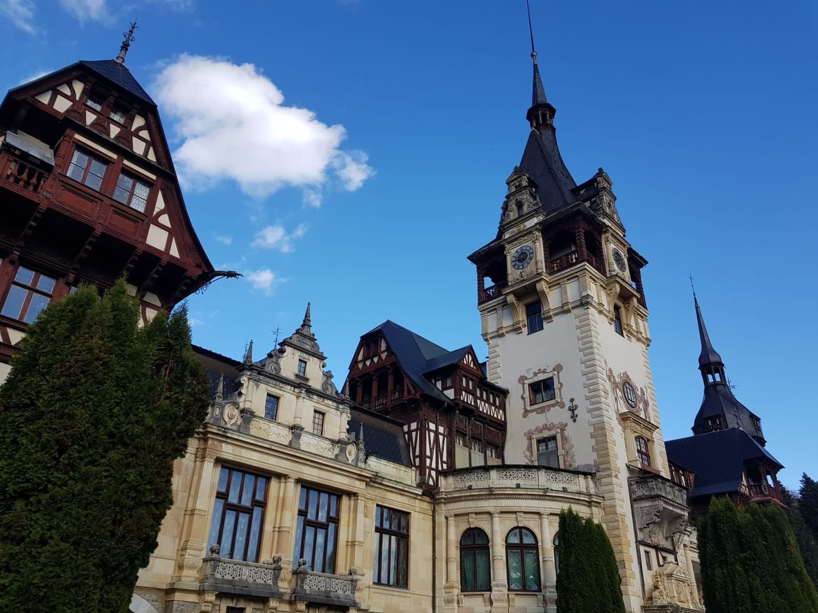 Ali a graticcio e torre dell'orologio del Castello di Peleș contro il cielo azzurro