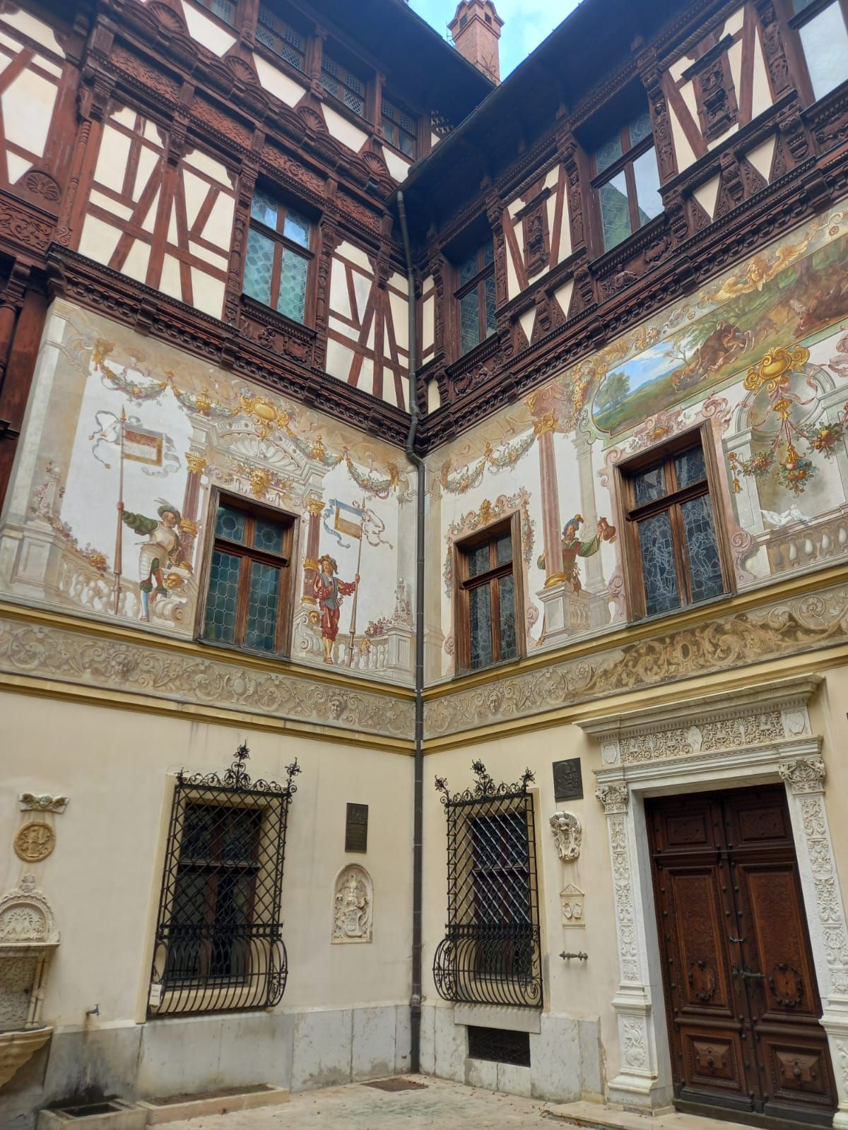 Turreted wing of Peleș Castle framed by evergreens