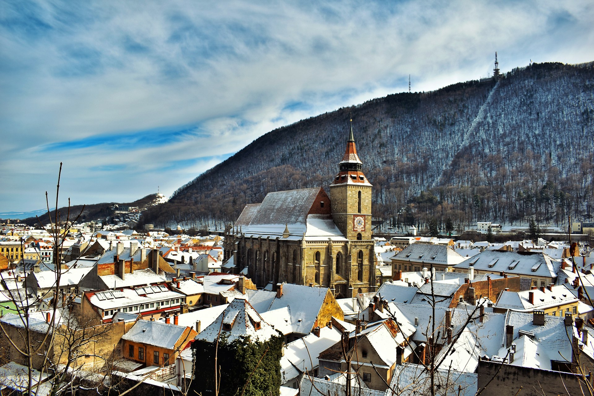 Snow-covered Brașov cityscape with mountain backdrop in winter