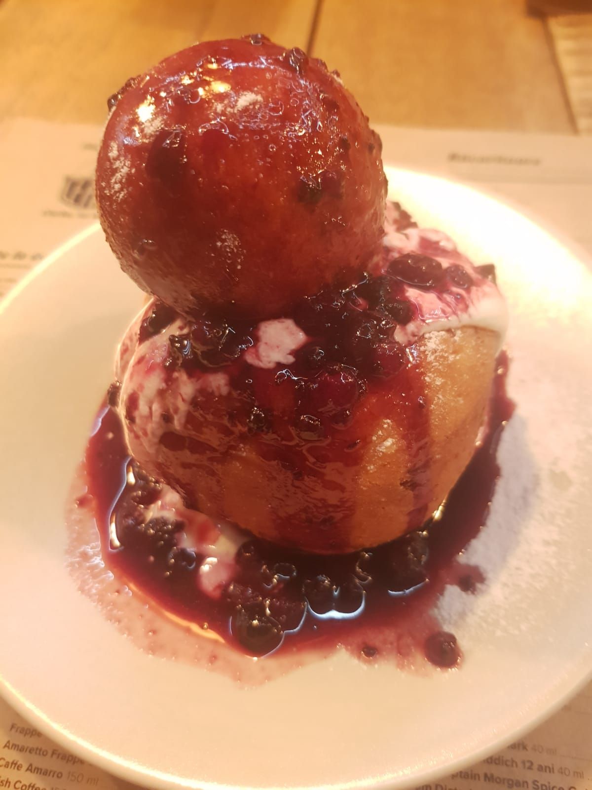 Plate of Romanian papanași topped with sour cream and jam