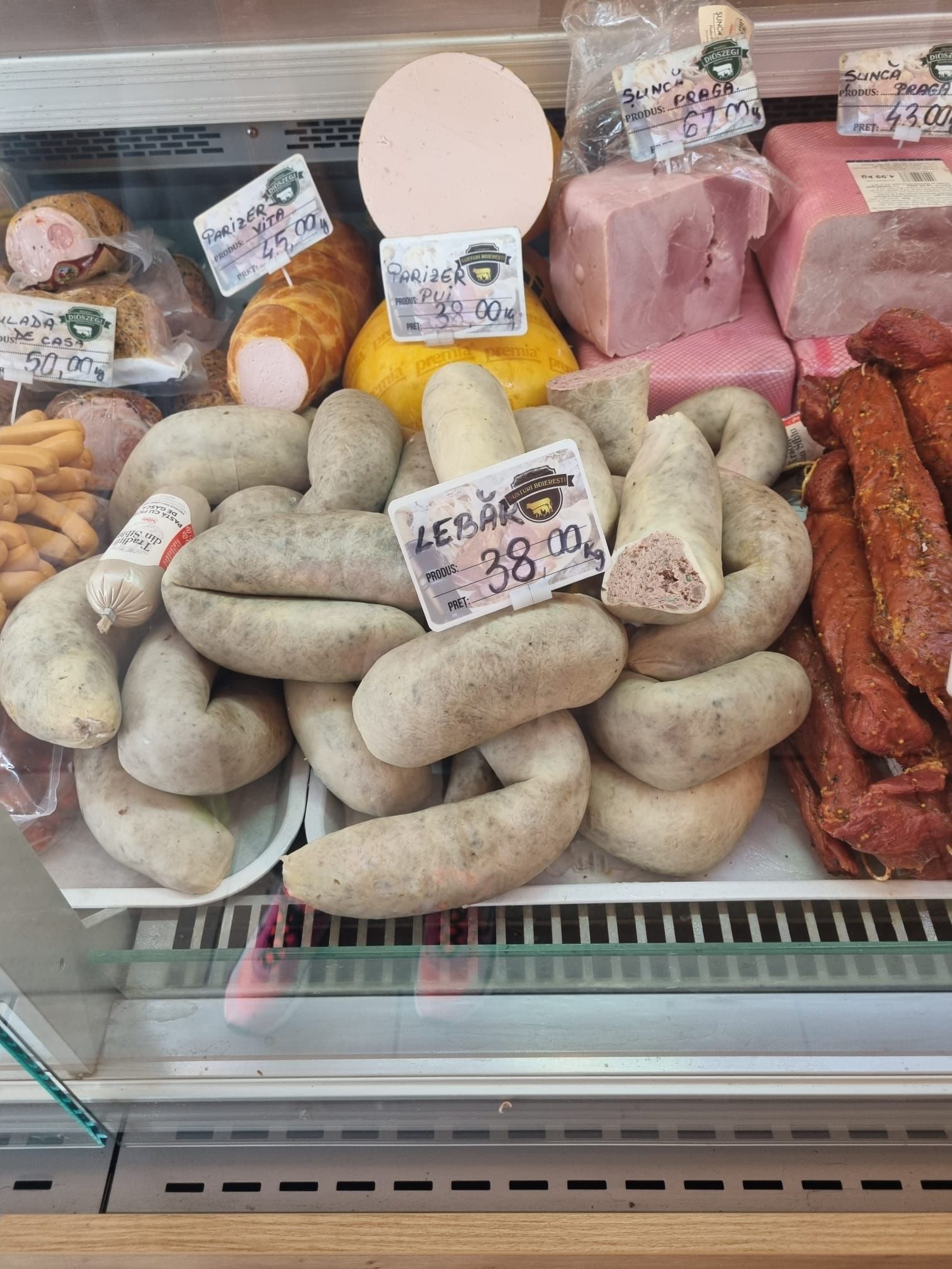 Kolbászok és sajtok egy hűtőpultban a Piața Tractorul piacán
