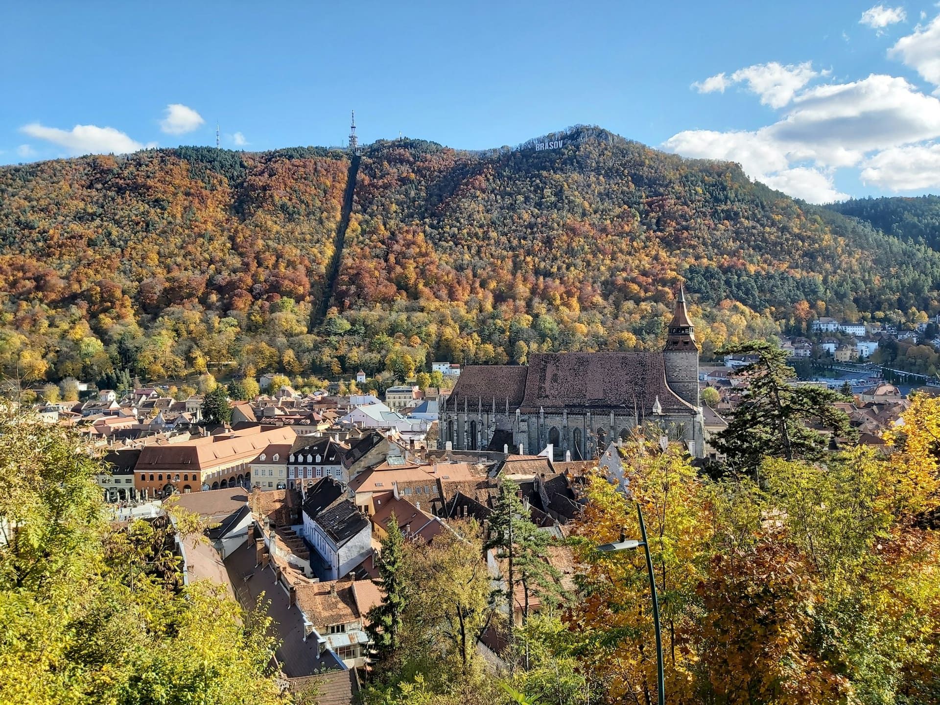 Vedere aeriană a Bisericii Negre din Brașov, încadrată de versantul împădurit al Tâmpei